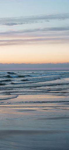 two surfers walking on the beach at sunset