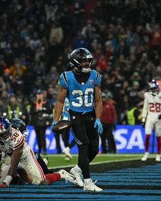 a football player running with the ball in his hand and other players on the field behind him