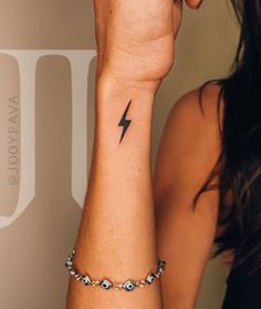 a woman's arm with a lightning tattoo on the left side of her wrist