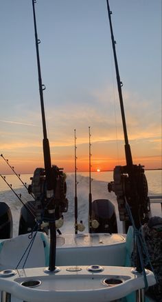 the sun is setting behind some fishing rods on a boat in the water with other boats