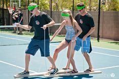 three people on a tennis court wearing blindfolds