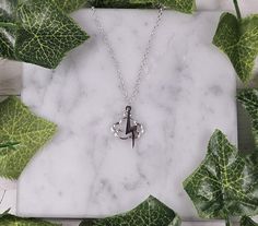 an anchor necklace on a marble background with green leaves