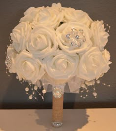 a bridal bouquet with white roses and diaper on the stems is sitting on a table