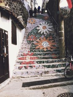 the stairs are painted with flowers and people walking up them in front of an open door