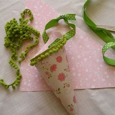 there is a paper cone with flowers on it next to some green ribbons and scissors