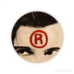 a close up of a button with a person's face and the letter r painted on it