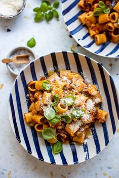 two bowls filled with pasta and sauce on top of a table