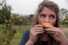 a woman holding an orange in her mouth