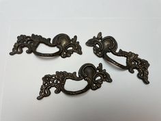 three antique style drawer pulls on a white surface