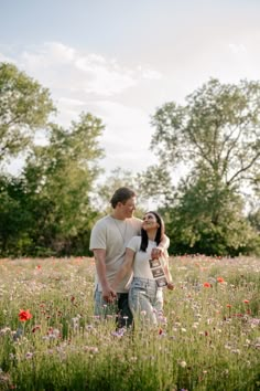 a man and woman standing in a field of flowers