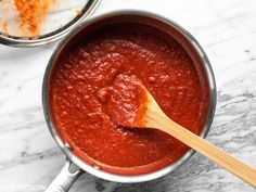 a wooden spoon in a saucepan filled with tomato sauce