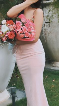 a woman in a pink dress holding a bouquet of roses