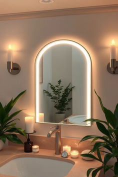 a bathroom sink sitting under a mirror next to a potted plant and two candles