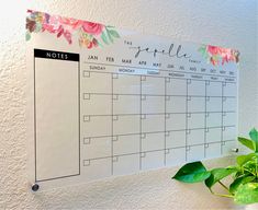 a calendar hanging on the wall next to a potted plant