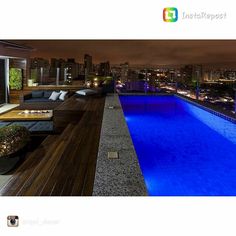 an outdoor swimming pool at night with city lights in the background