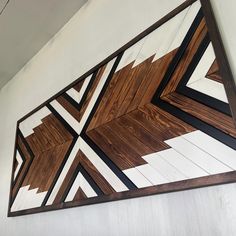 a wood and metal wall hanging on the side of a building with geometric designs painted on it