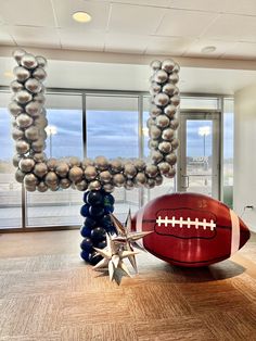 a football balloon arch in the shape of a star and some balloons are hanging from it's ceiling