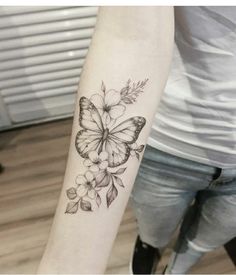 a woman's arm with a butterfly and flowers tattoo on the left inner forearm