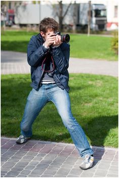 a man taking a photo with his camera on the sidewalk in front of some grass