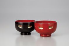 two black and red bowls sitting on top of a white table next to each other