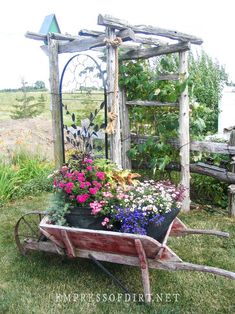 a wheelbarrow with flowers in it sitting on the grass