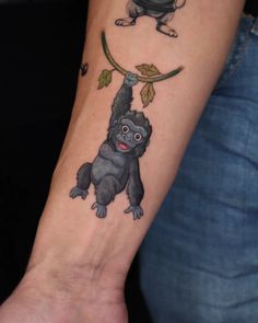 a small monkey tattoo on the wrist and arm, with an apple hanging from it's tree branch