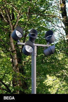 there are three lights on the pole in front of some tree's and leaves