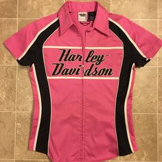 a pink and black shirt that says harley davidson on the front, sitting on a tile floor