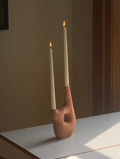 two candles sitting on top of a white table