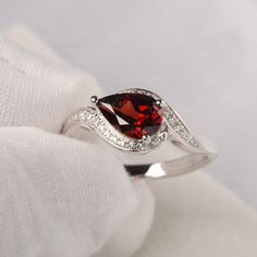 a close up view of a ring with a garnet stone in the center and diamond accents around it