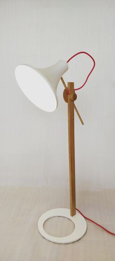 a lamp that is on top of a wooden stand with a red cord attached to it