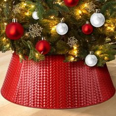 a christmas tree in a red basket with white and red ornaments on it's top