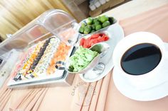 a table topped with plates and bowls filled with different types of food next to a cup of coffee