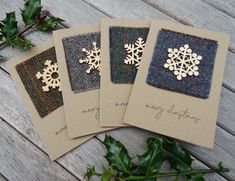 three cards with snowflakes on them are sitting next to holly leaves and greenery