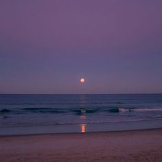 the moon is setting over the ocean with waves