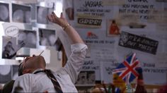 a man in white shirt and tie standing next to wall with posters on it's walls