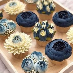 cupcakes decorated with blue and white flowers on a wooden tray