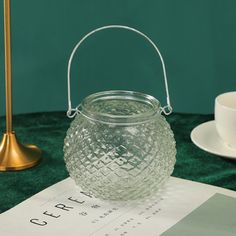 a glass jar sitting on top of a table next to a cup and saucer