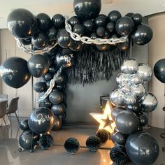 black and silver balloons are hanging from the ceiling in front of an arch with a star