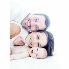 a man, woman and baby laying on top of each other