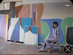 a woman sitting on a chair in front of paintings