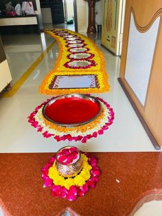 a long row of flower petals on the ground with a vase and bowl in front