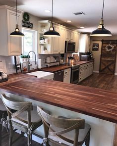 a kitchen with white cabinets and wooden counter tops, two chairs are facing the island