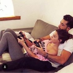 a man and woman are sitting on a couch playing video games with remote controllers in their hands