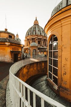 an old building with two domes on top and a white fence around the outside area