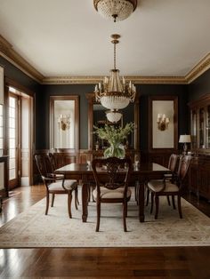 an elegant dining room with chandelier and wooden floors, dark walls and wood trimmings