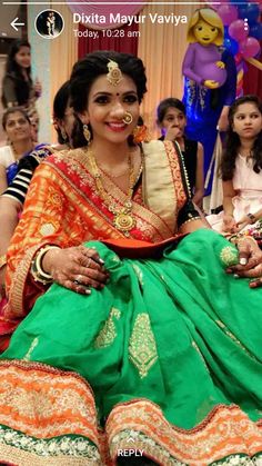 a woman in an orange and green sari sitting on the ground with other people