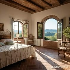 a bedroom with an arched window and stone flooring, overlooking the countryside outside it