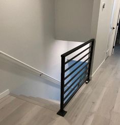 an empty hallway with white walls and black railings on the bottom half of the stairs