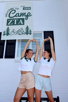 two young women standing next to each other in front of a building